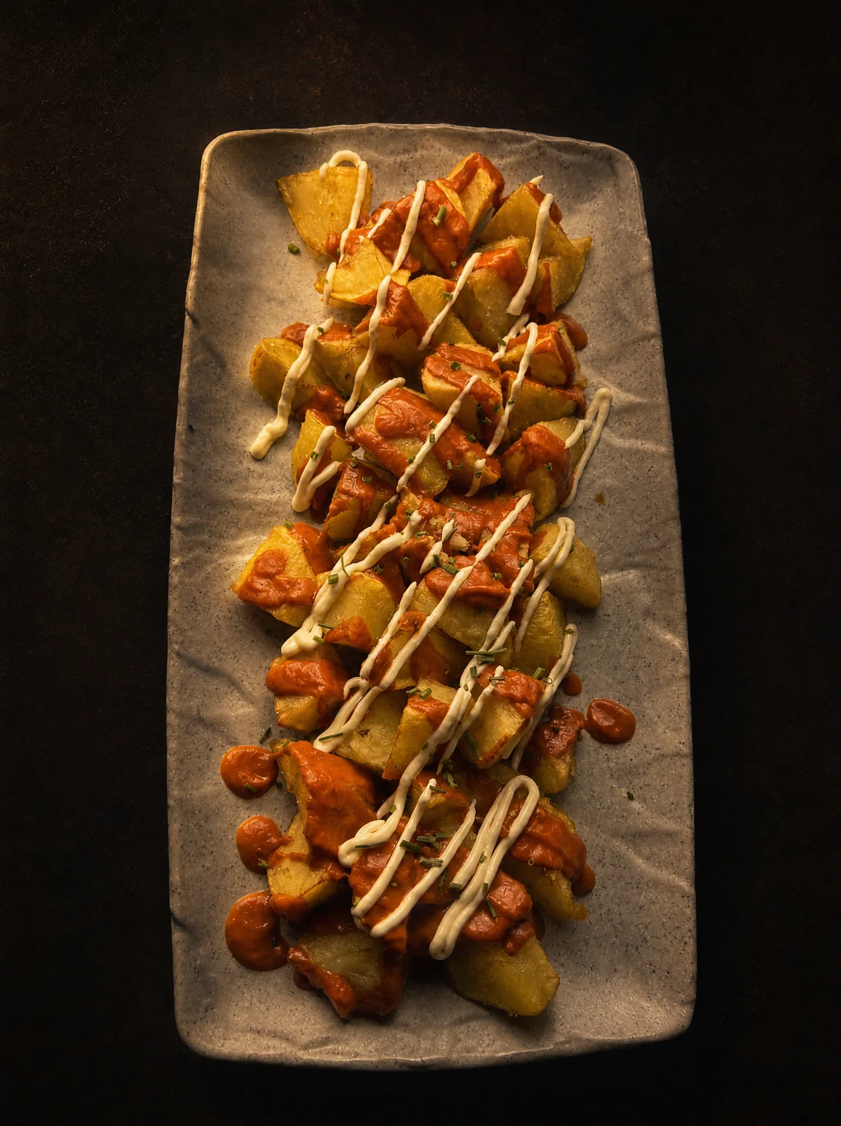 Patatas bravas con salsa brava y alioli de La Caleta Manchega