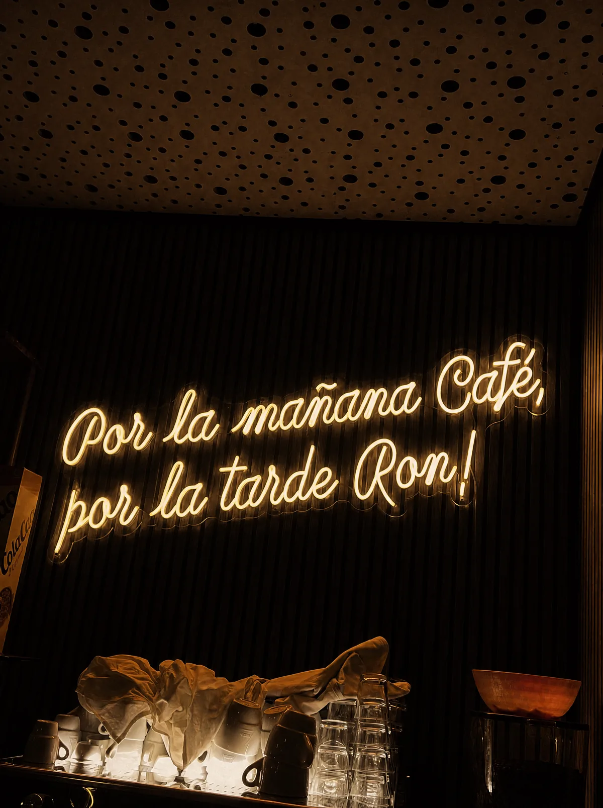 Cartel de neón 'Por la mañana Café, por la tarde Ron' sobre la barra de cafés